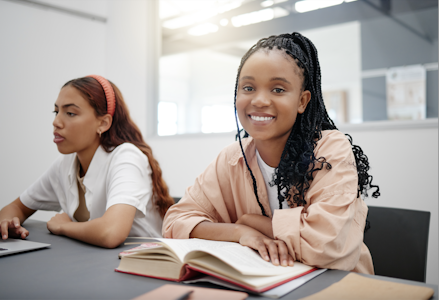 Two female college students in class. What is student retention in higher ed?