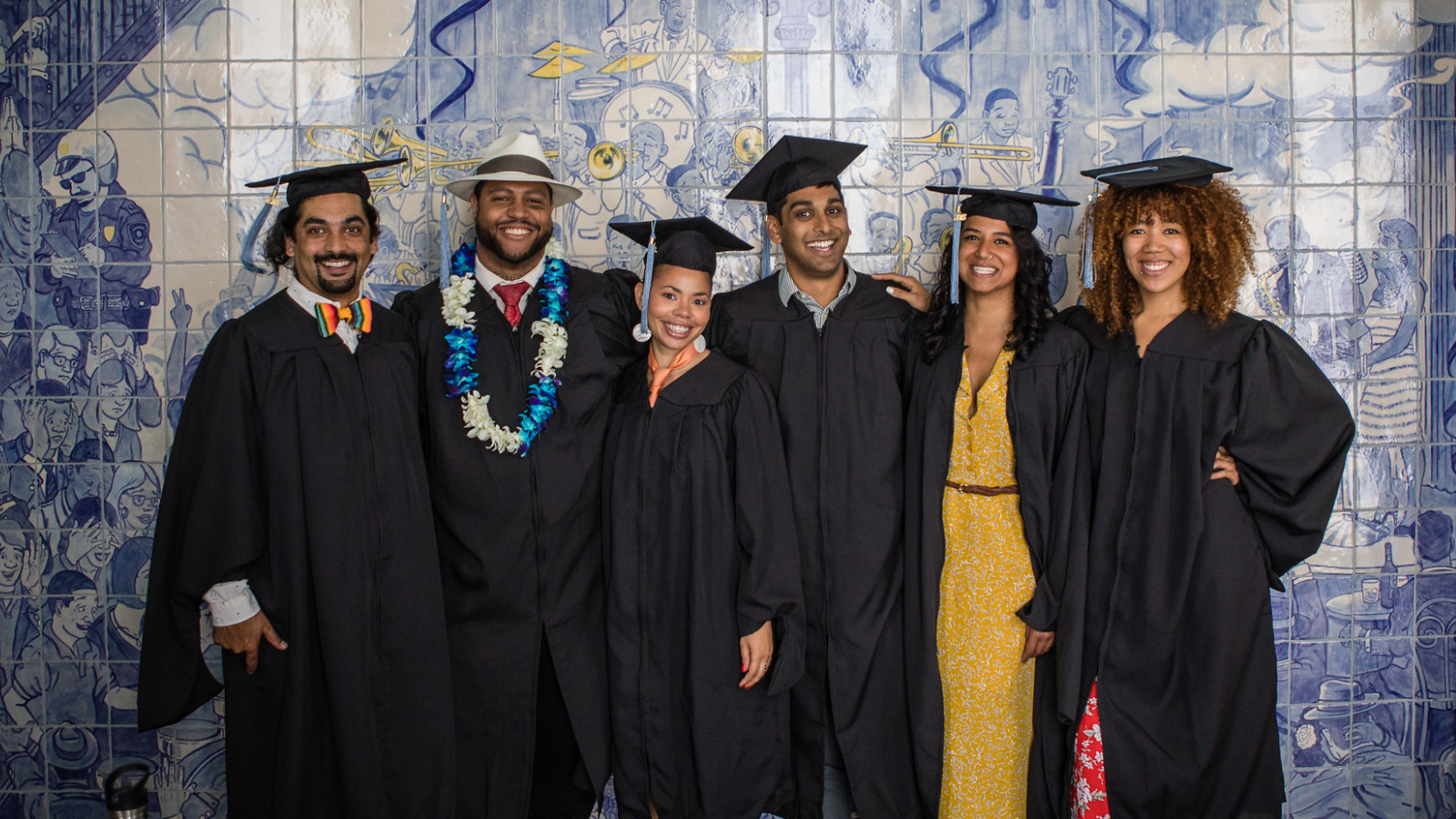 A group of graduates from Presidio Graduate School wearing graduation robes and mortar board caps.