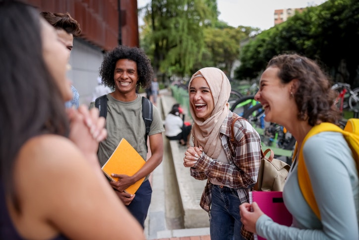 Photo of a diverse group of students laughing together. These students have been offered direct admissions and converted due to increased engagement.