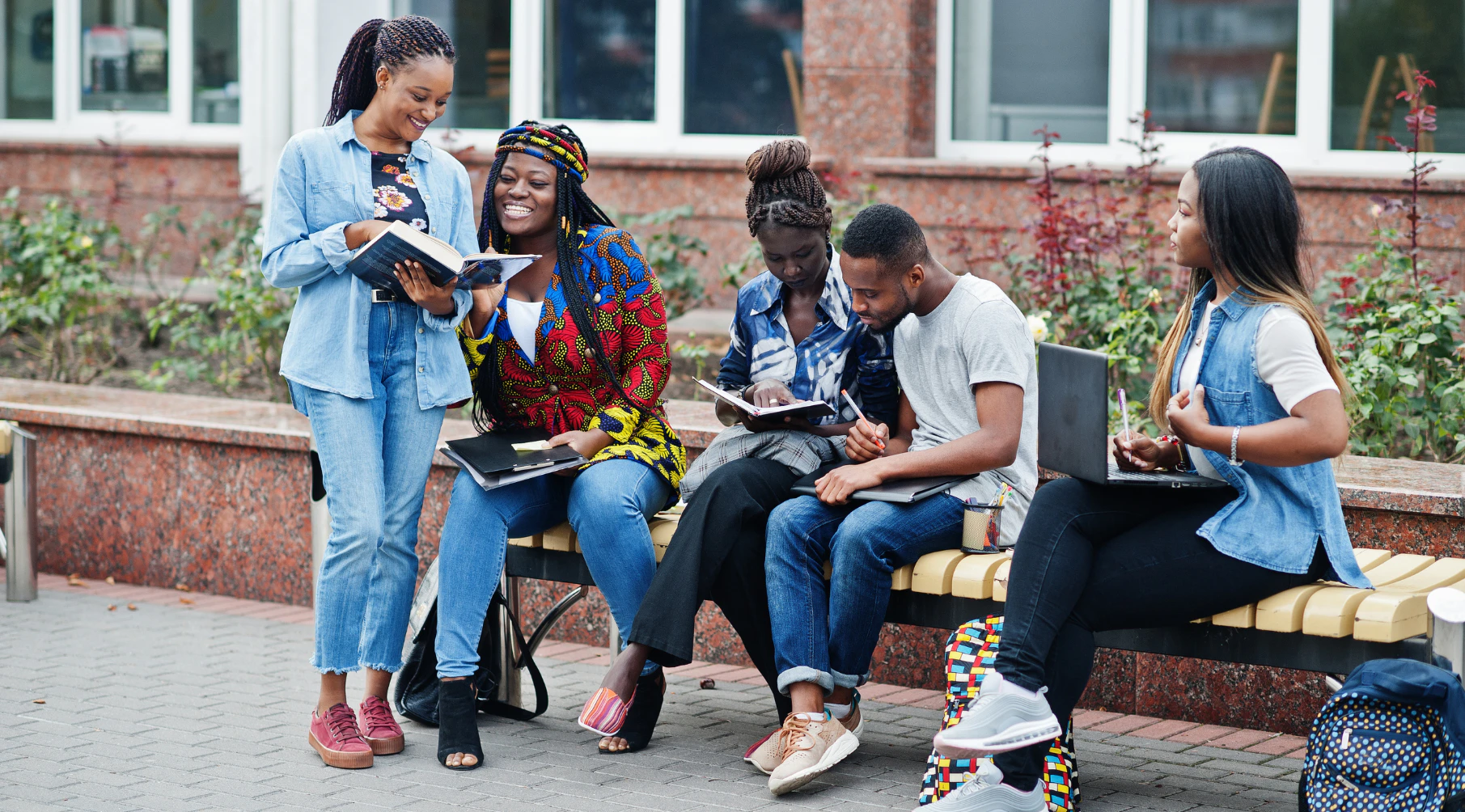 College students studying together on a bench outside a campus building