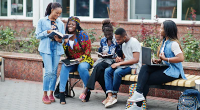 College students studying together on a bench outside a campus building