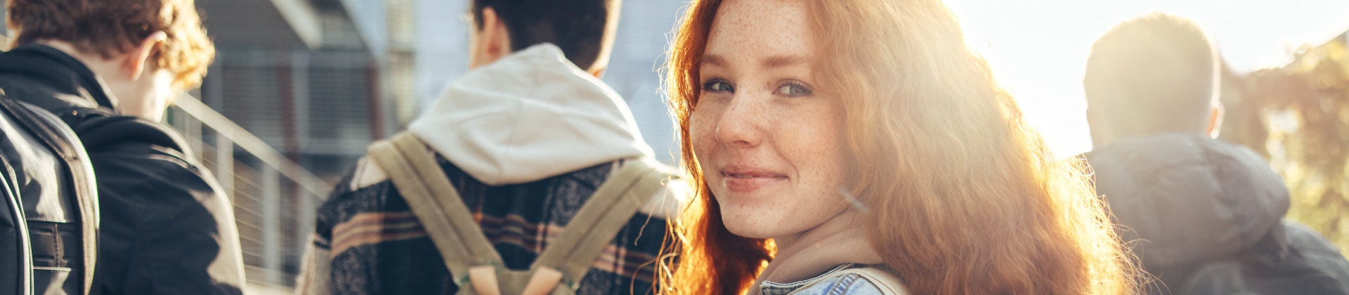 Girl college student walking behind a group of other students and looking behind her.