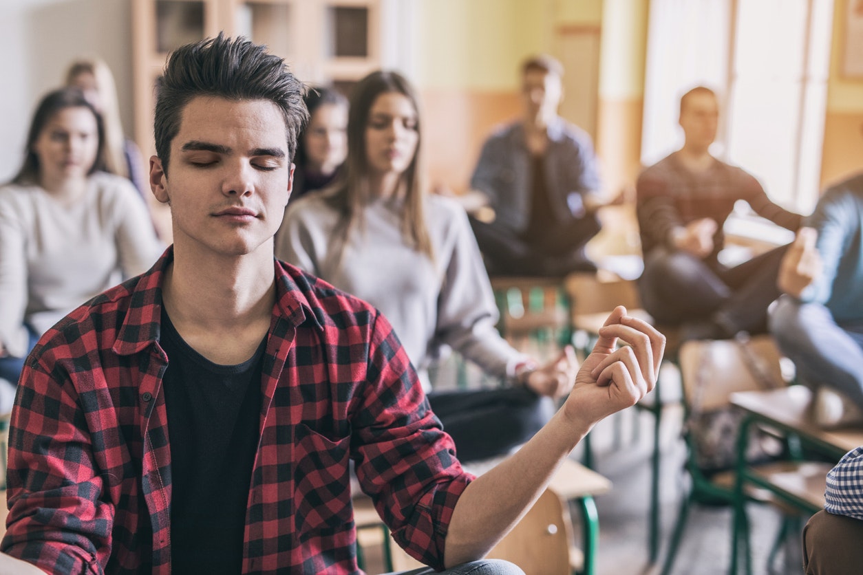 College students sitting on desks meditating