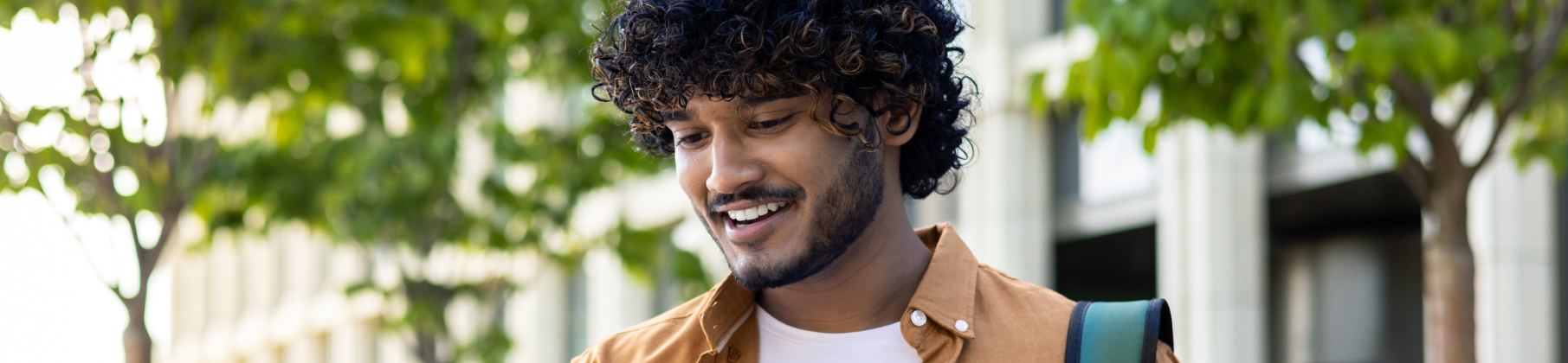 College student looking down at his phone and smiling.