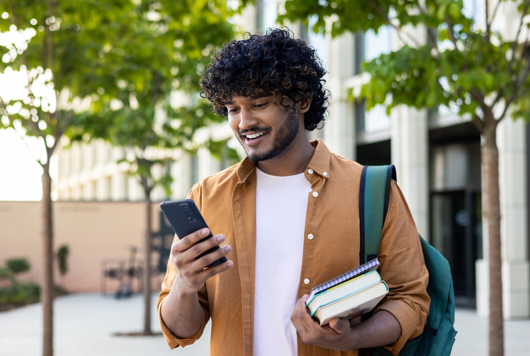 College student looking down at his phone and smiling.
