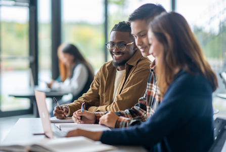 3 college students in a classroom working on a group project together.