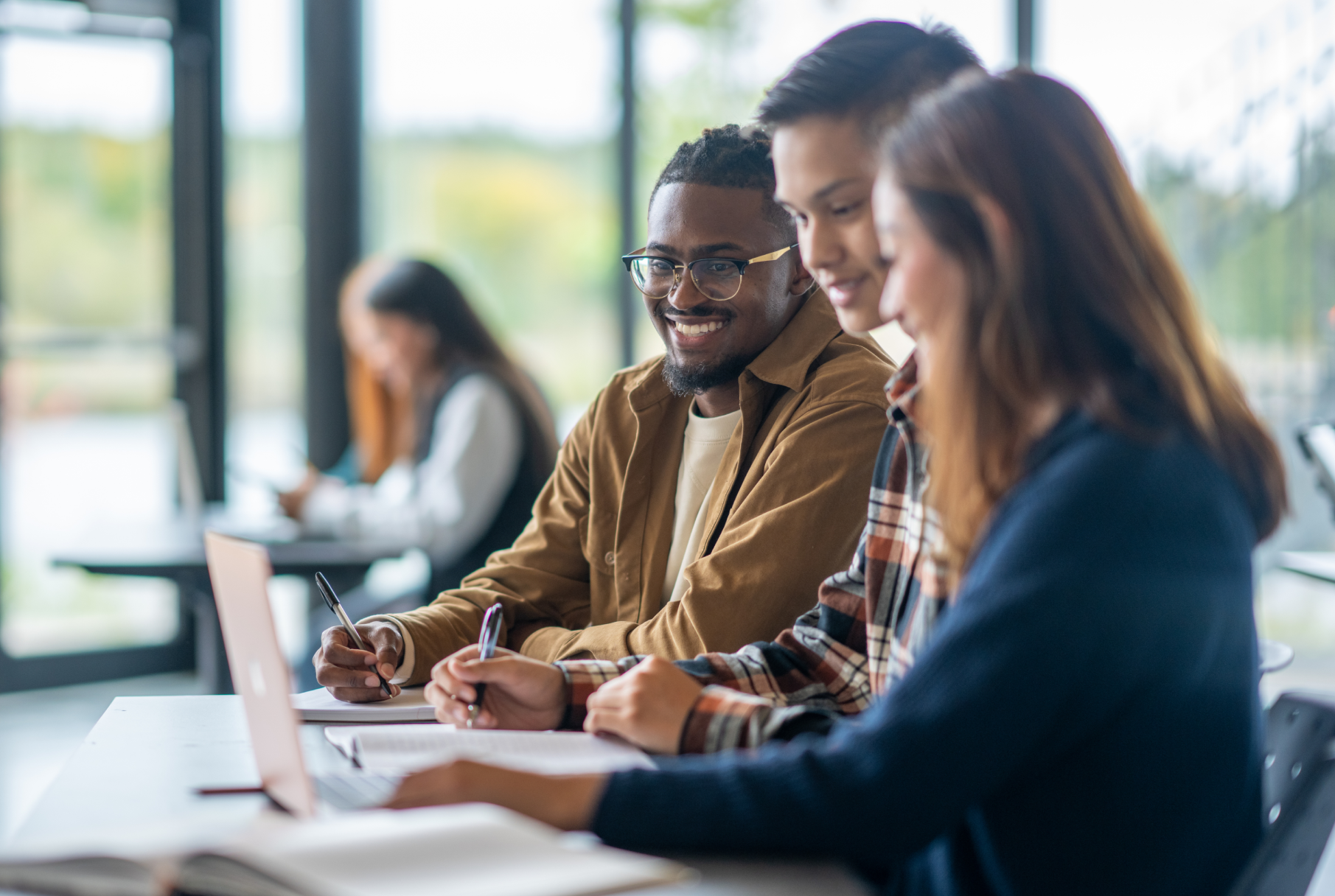 3 college students in a classroom working on a group project together.