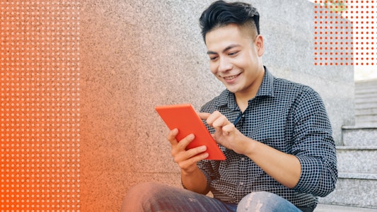 Male student smiles working on a tablet.