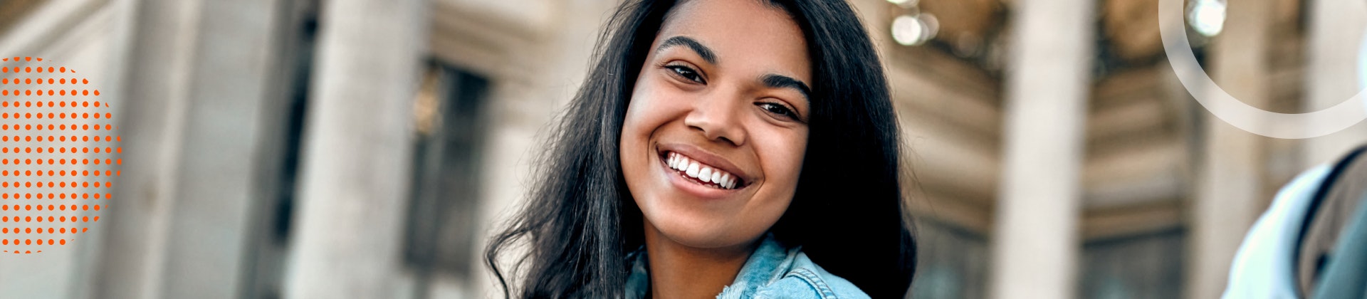 A young female student holding a phone and smiling.