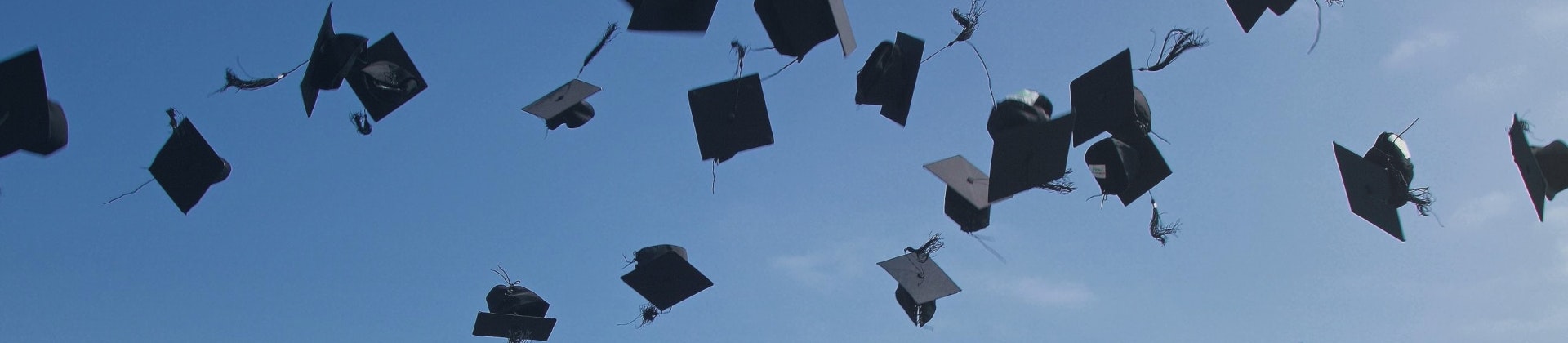 Image of students throwing their graduation caps in the air.