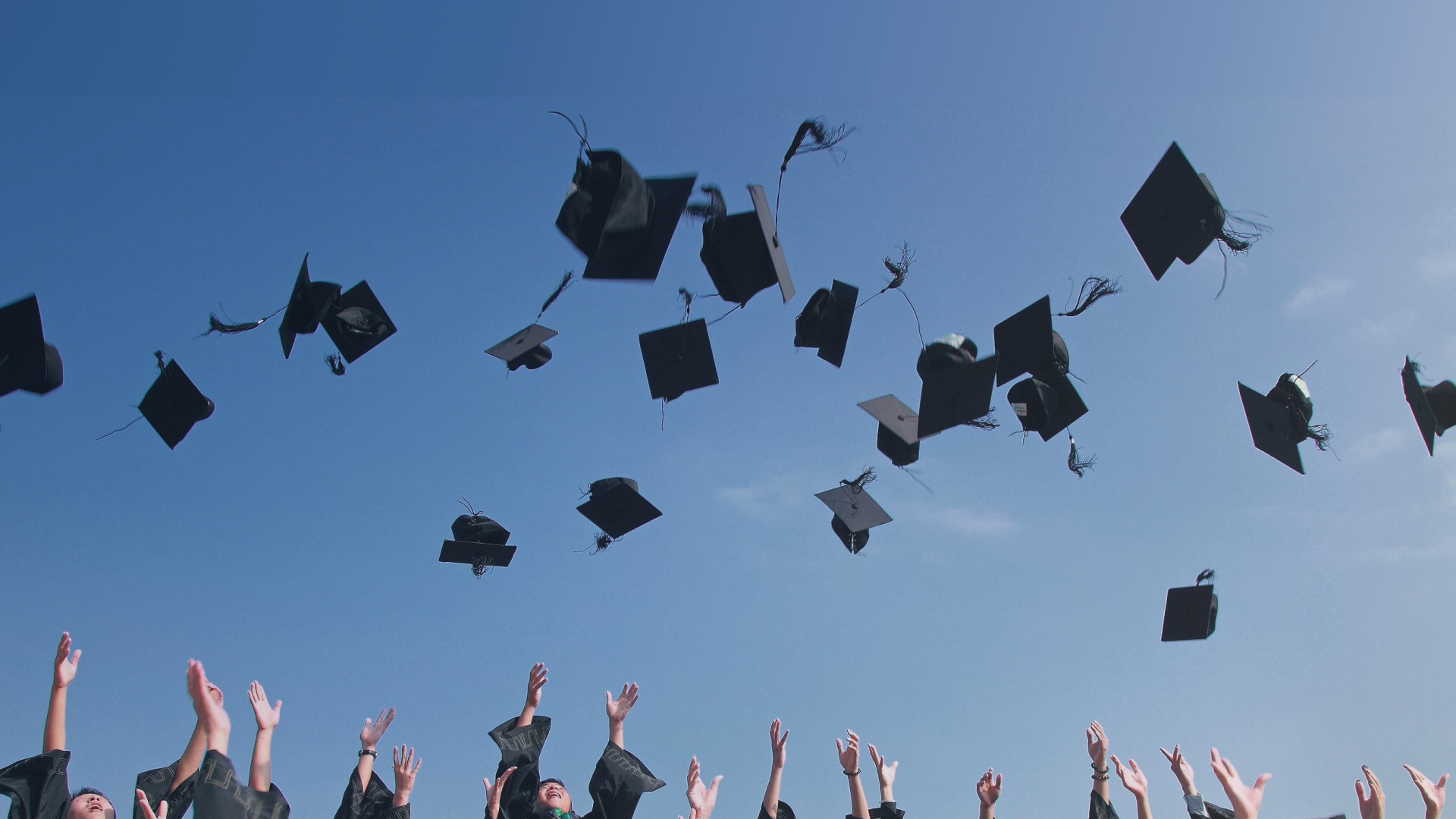 Image of students throwing their graduation caps in the air.