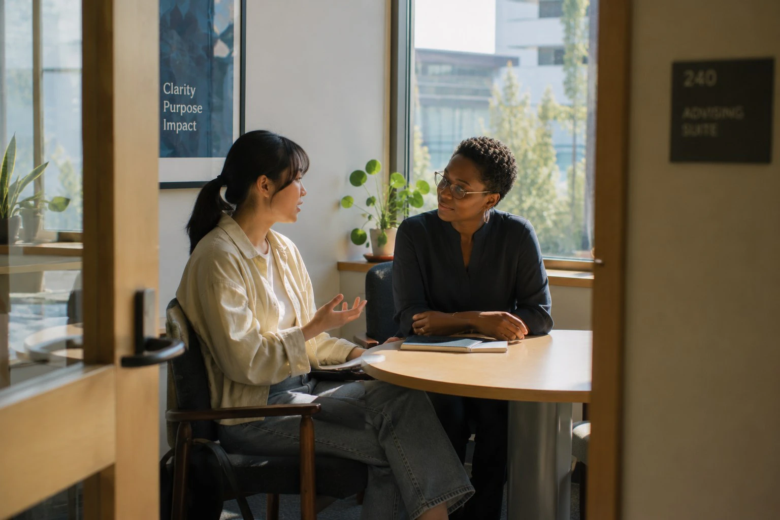 A student and an advisor talking at a table in a campus advising suite