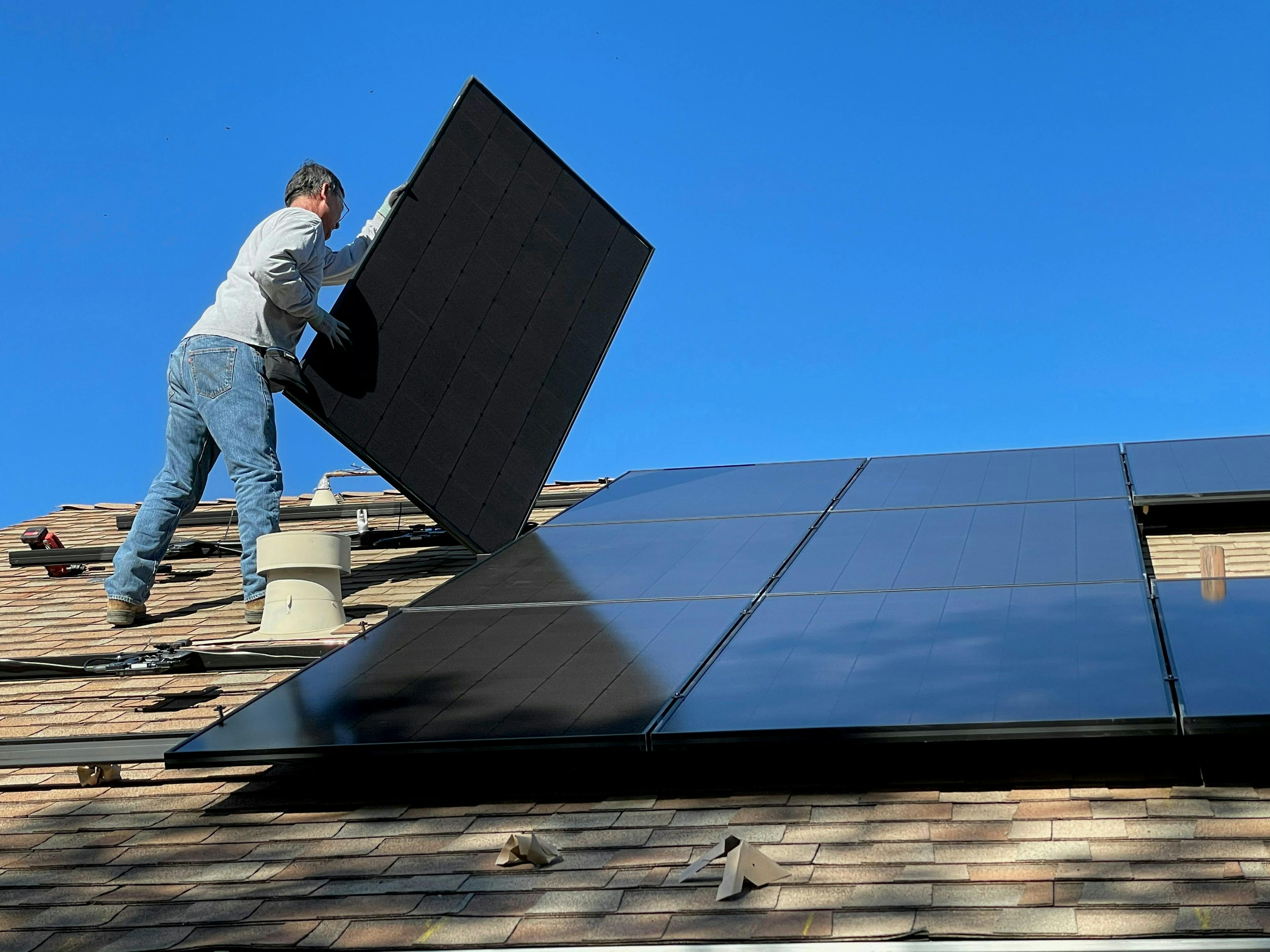 A guy installing solar panels on top of a roof