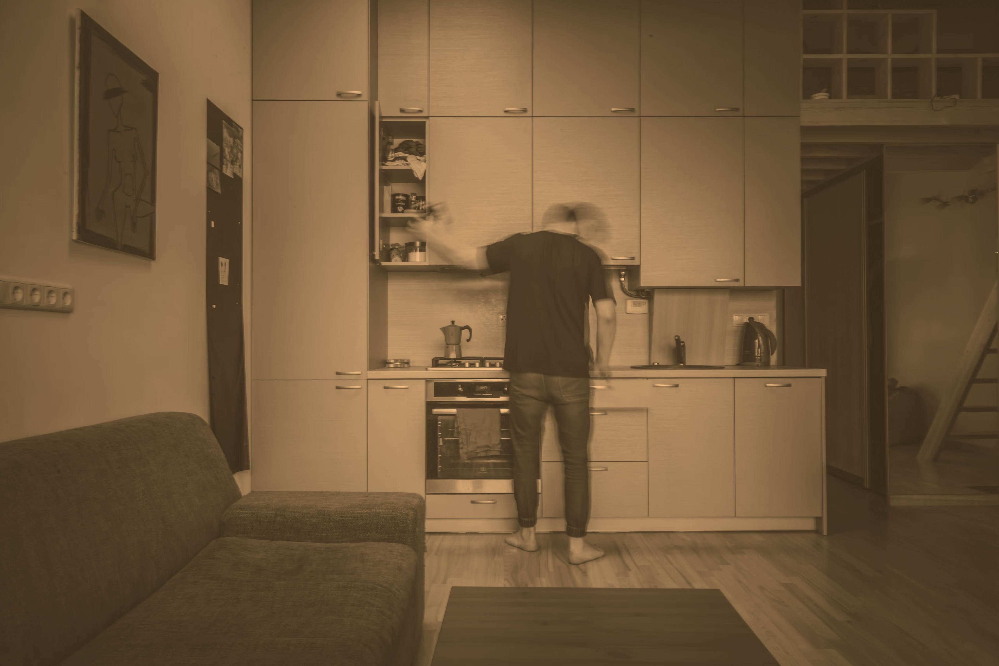 A guy in his kitchen making food 

