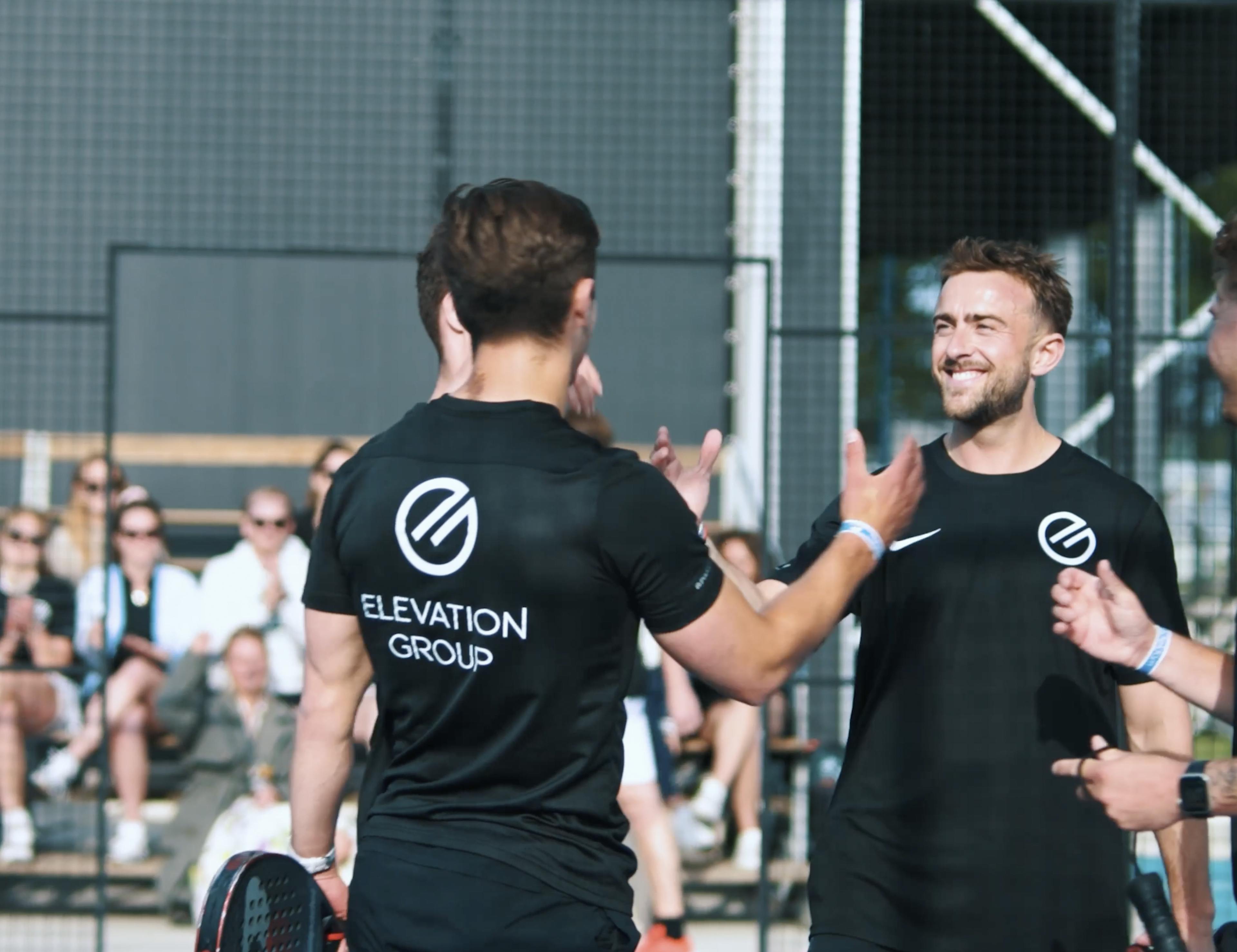 Collega's schudden elkaar de hand op padeltoernooi.