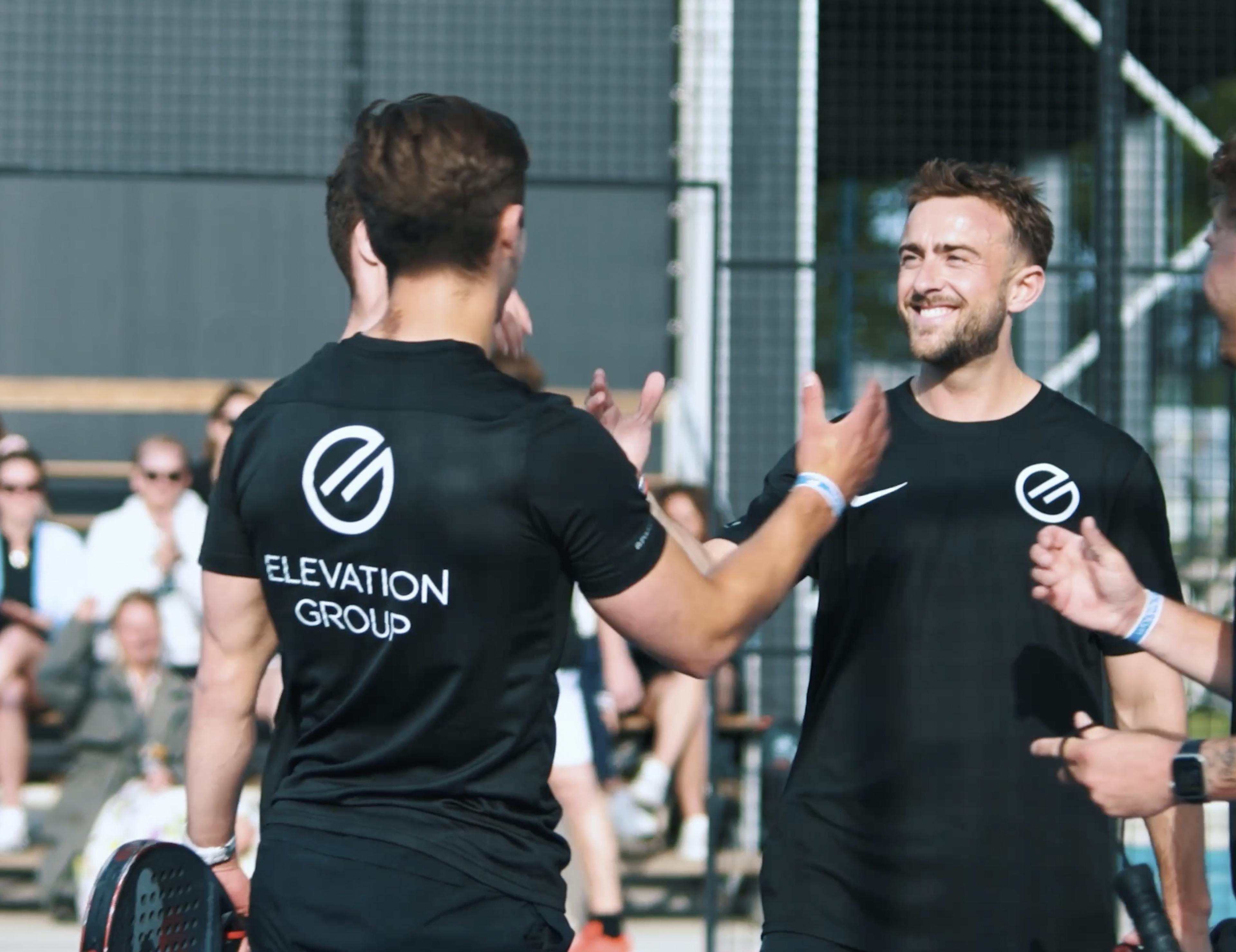 Collega's schudden elkaar de hand op padeltoernooi.