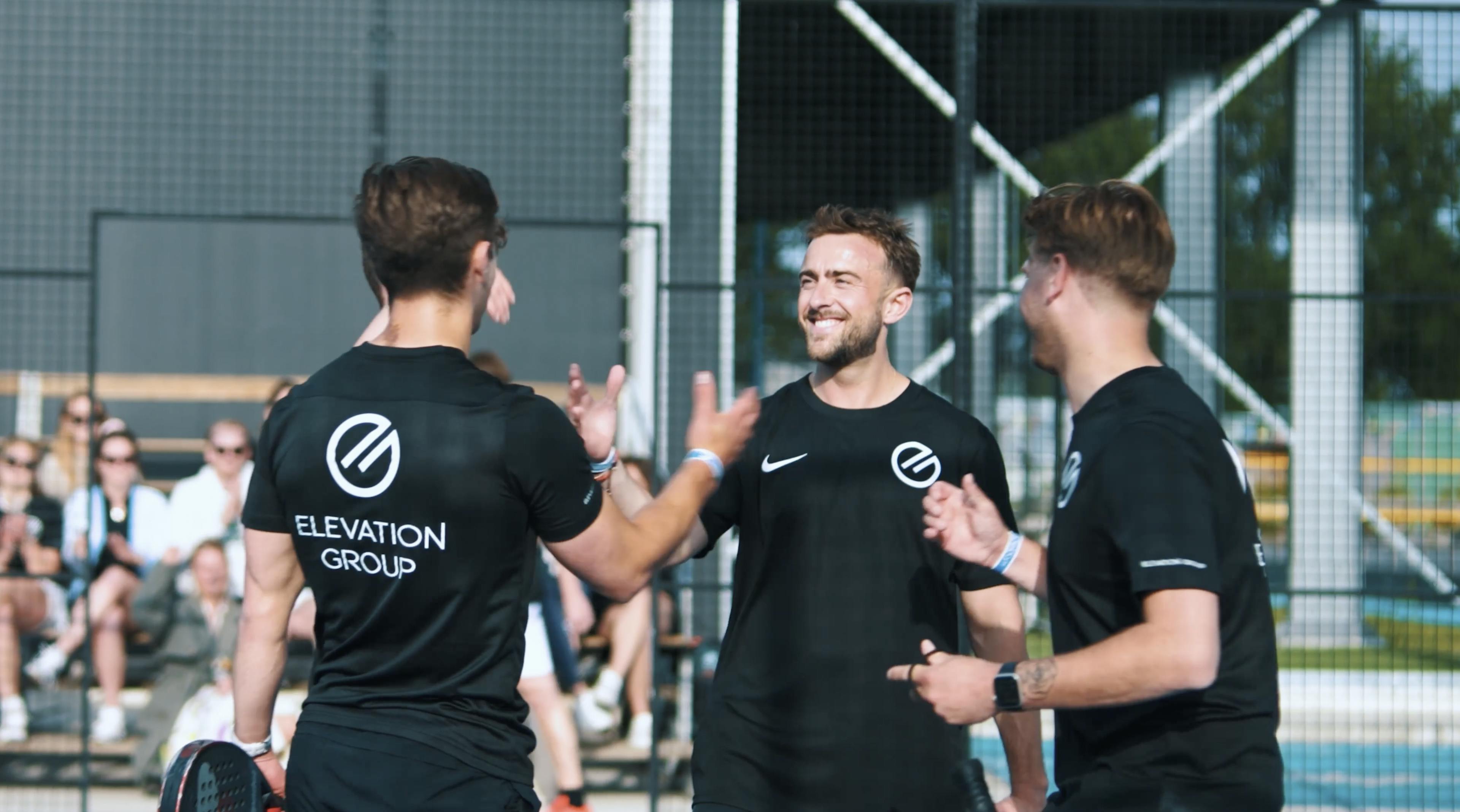 Collega's schudden elkaar de hand op padeltoernooi.