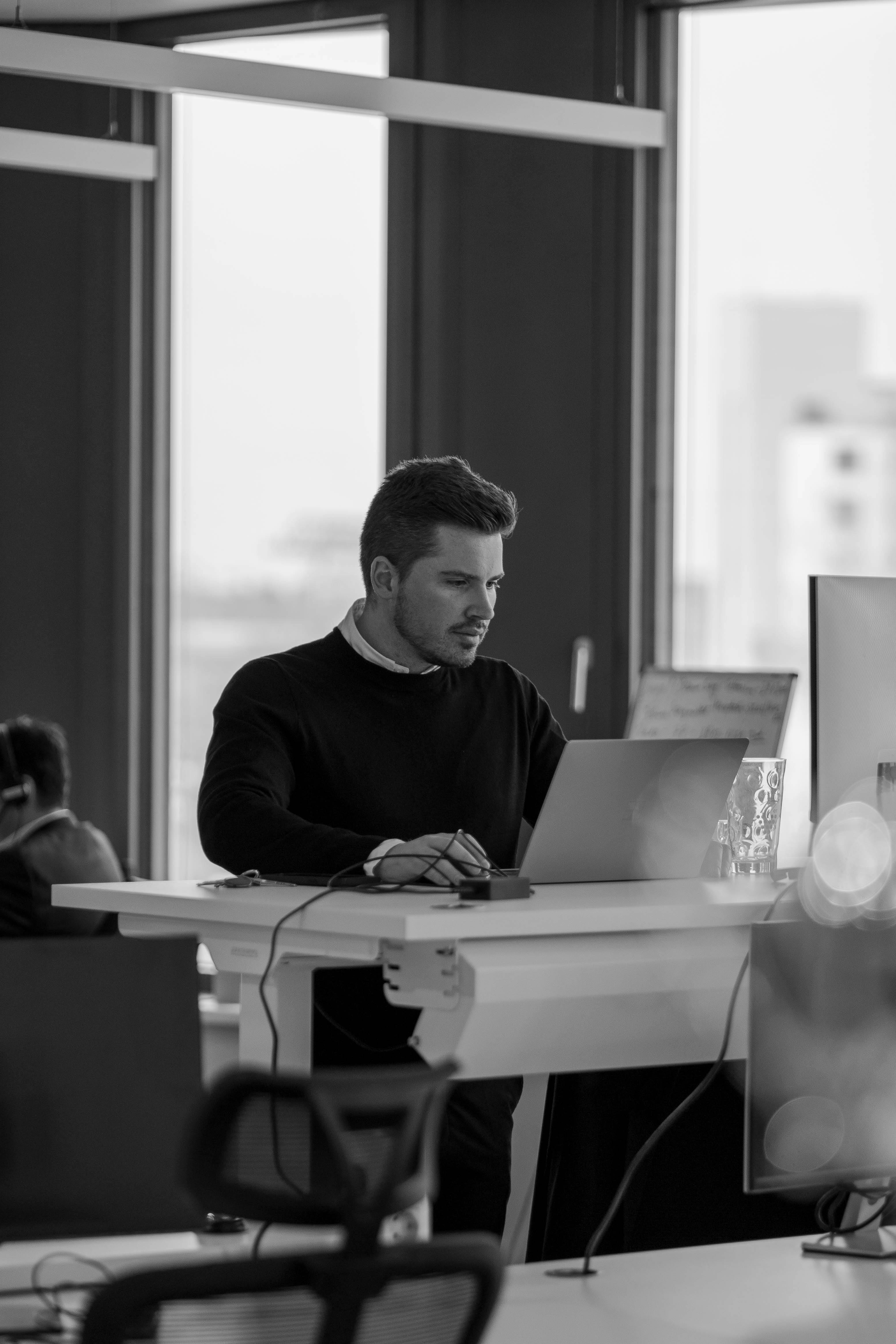 Zwart wit foto van een werknemer achter laptop.