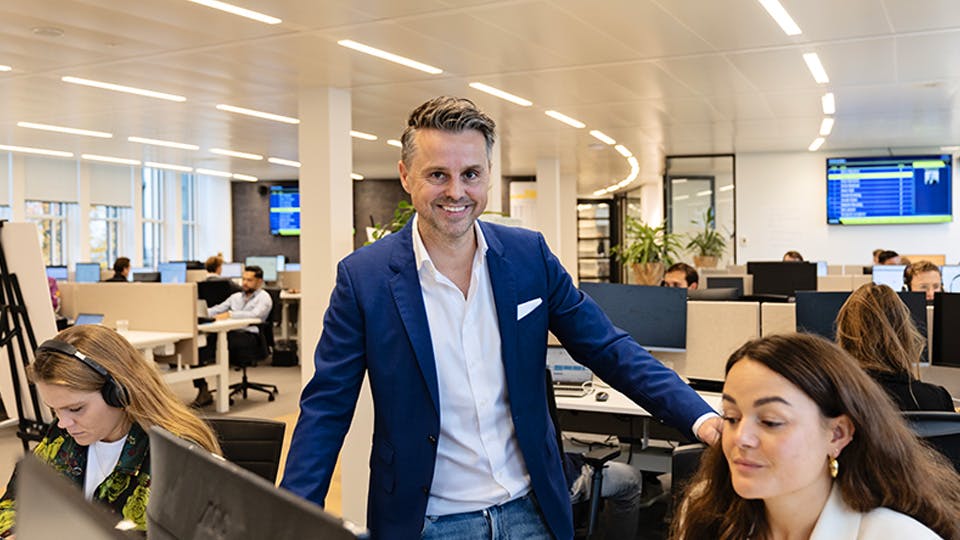 Collega op de salesvloer die lachend in de camera kijkt.