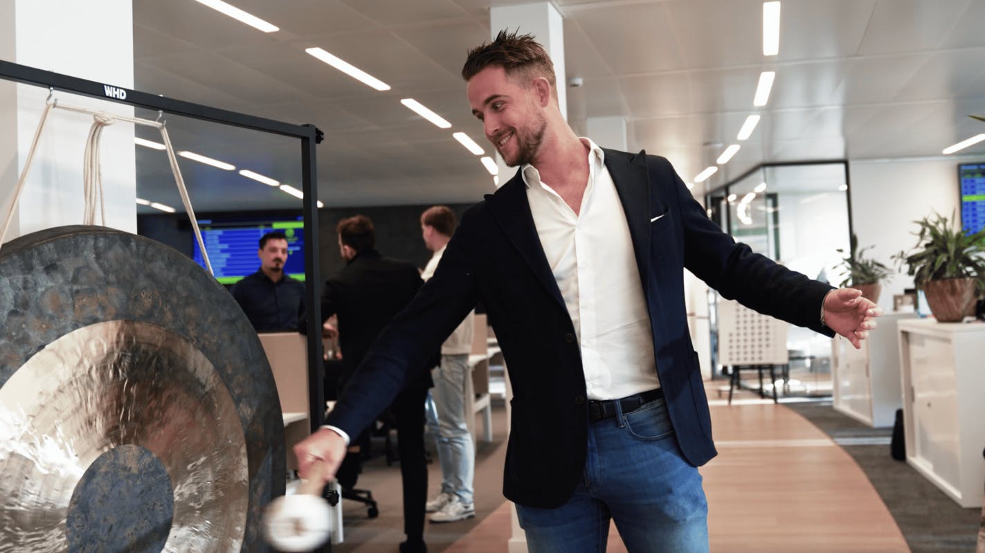 Collega die op de gong slaat als er een deal wordt gemaakt.