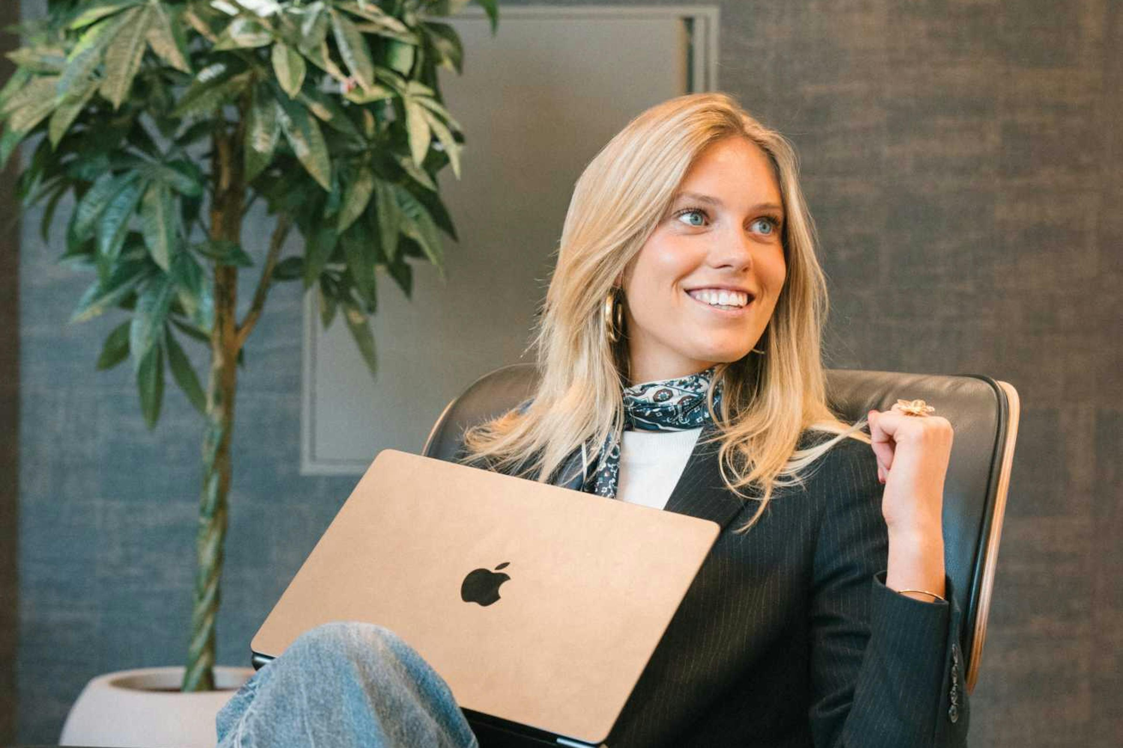 Willemijn zit in een luxe bureaustoel in de lobby van het kantoor van Elevation Group met een laptop op schoot. 