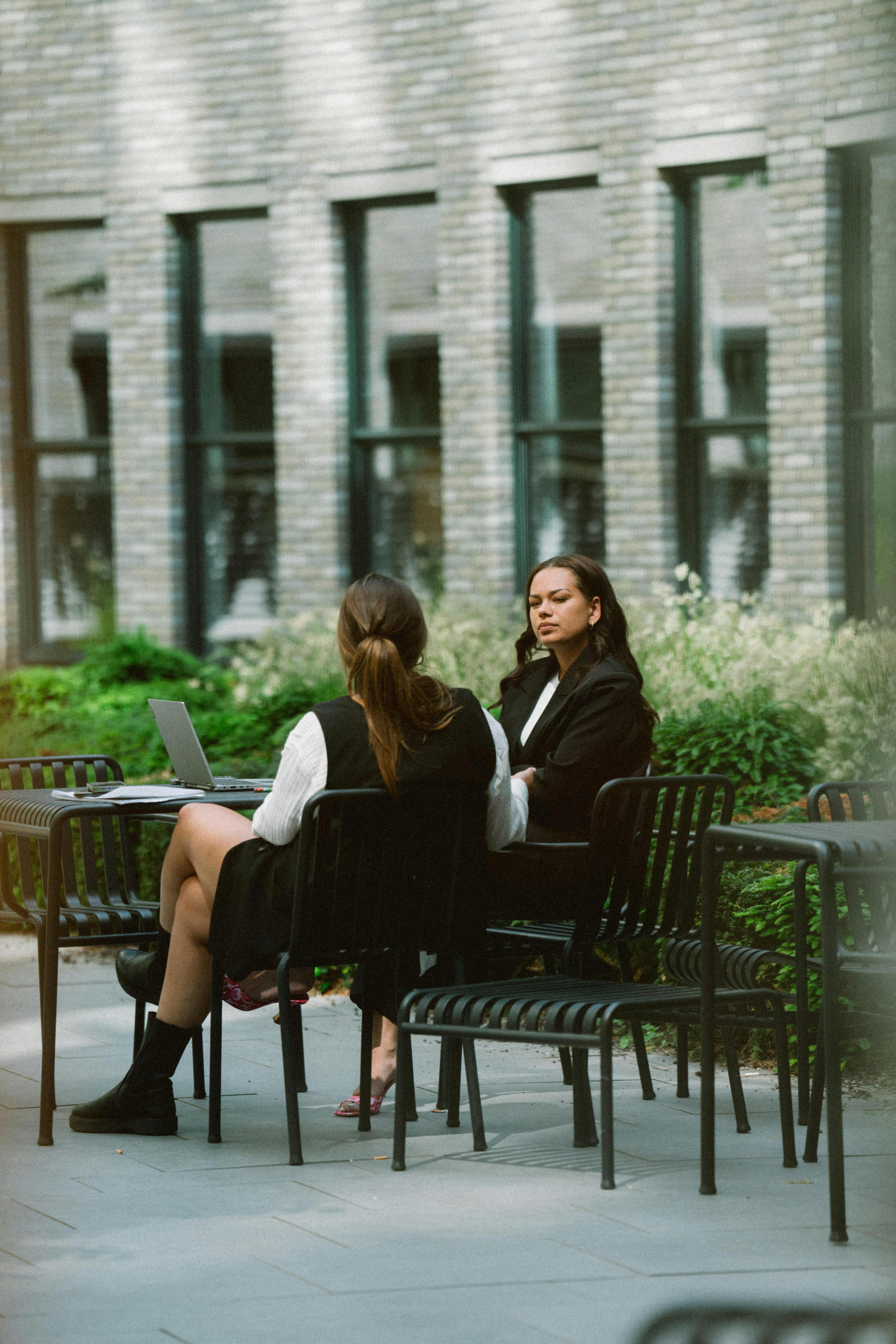 Twee medewerksters in gesprek in de buitenruimte van het Elevation Partners kantoor.