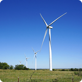 White wind turbines of a wind farm on open farmland against a blue sky