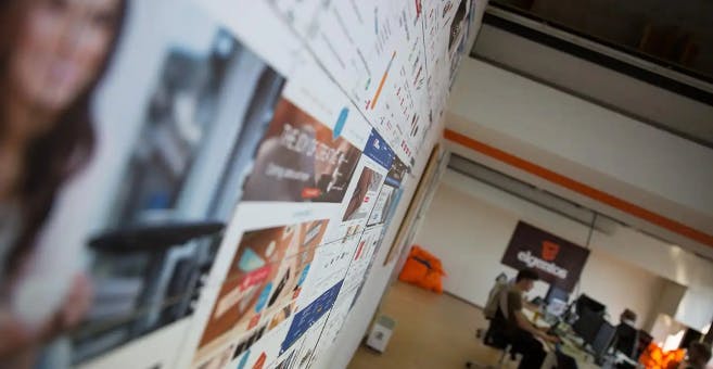 Wall filled with logos and pictures with Elgentos employees in the background