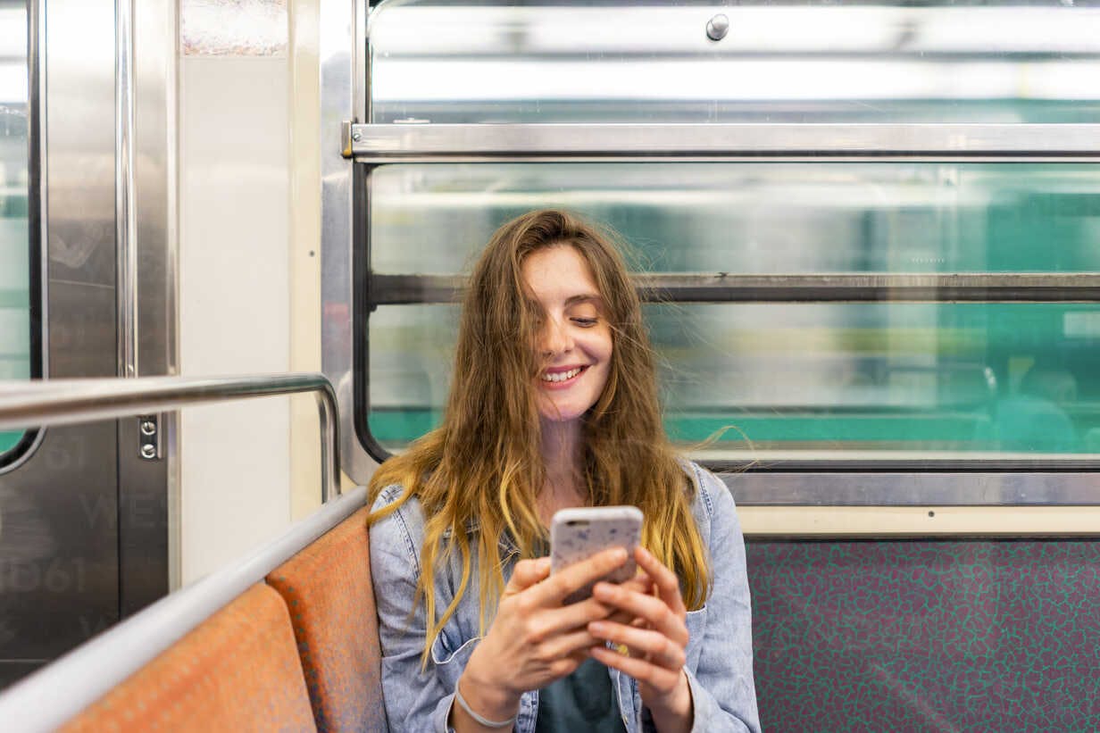 Femme sur son téléphone qui sourit dans le metro