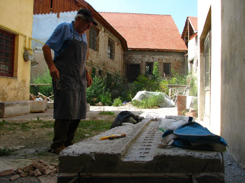 Emil Mureșan privind una dintre sculpturile sale în piatră