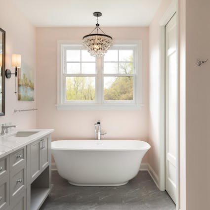 pink and grey bathroom, standing tub, chandelier hanging above tub