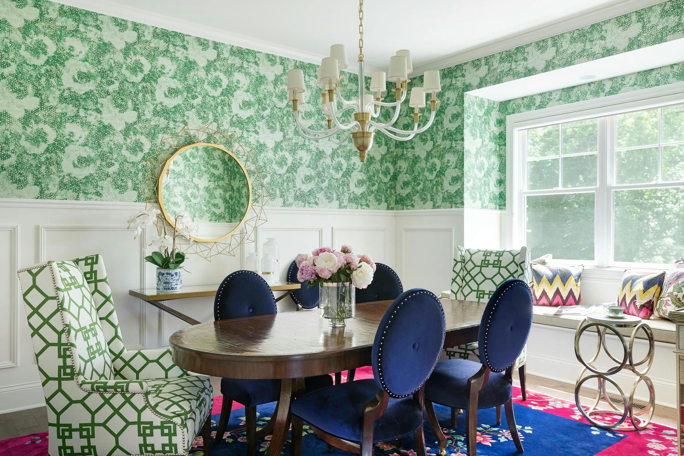 colorful dining room with green wall paper, blue velvet chairs and touches of gold