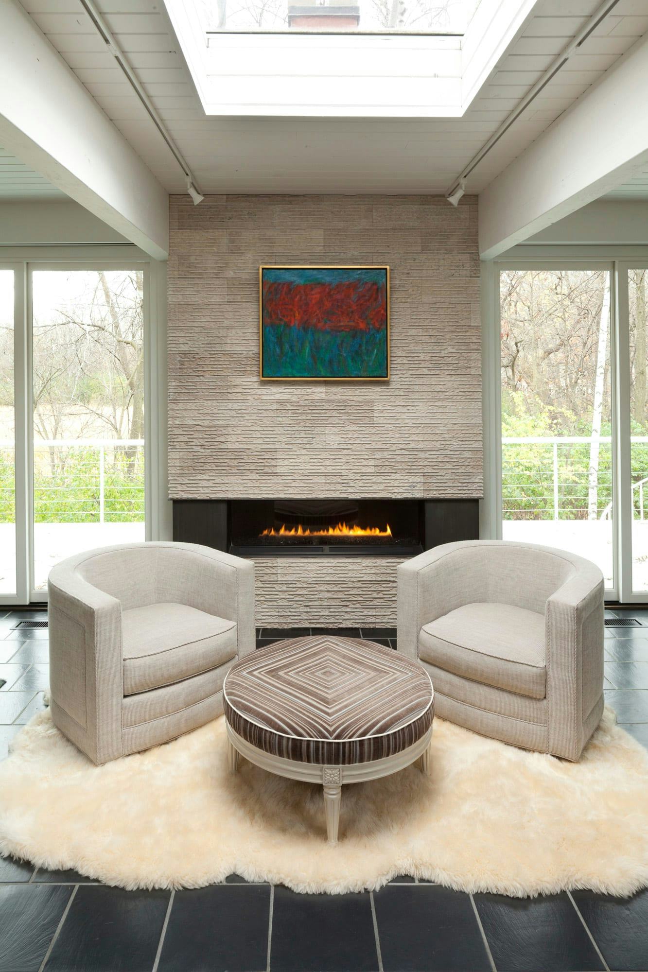 fireplace with two chairs, rug and ottoman
