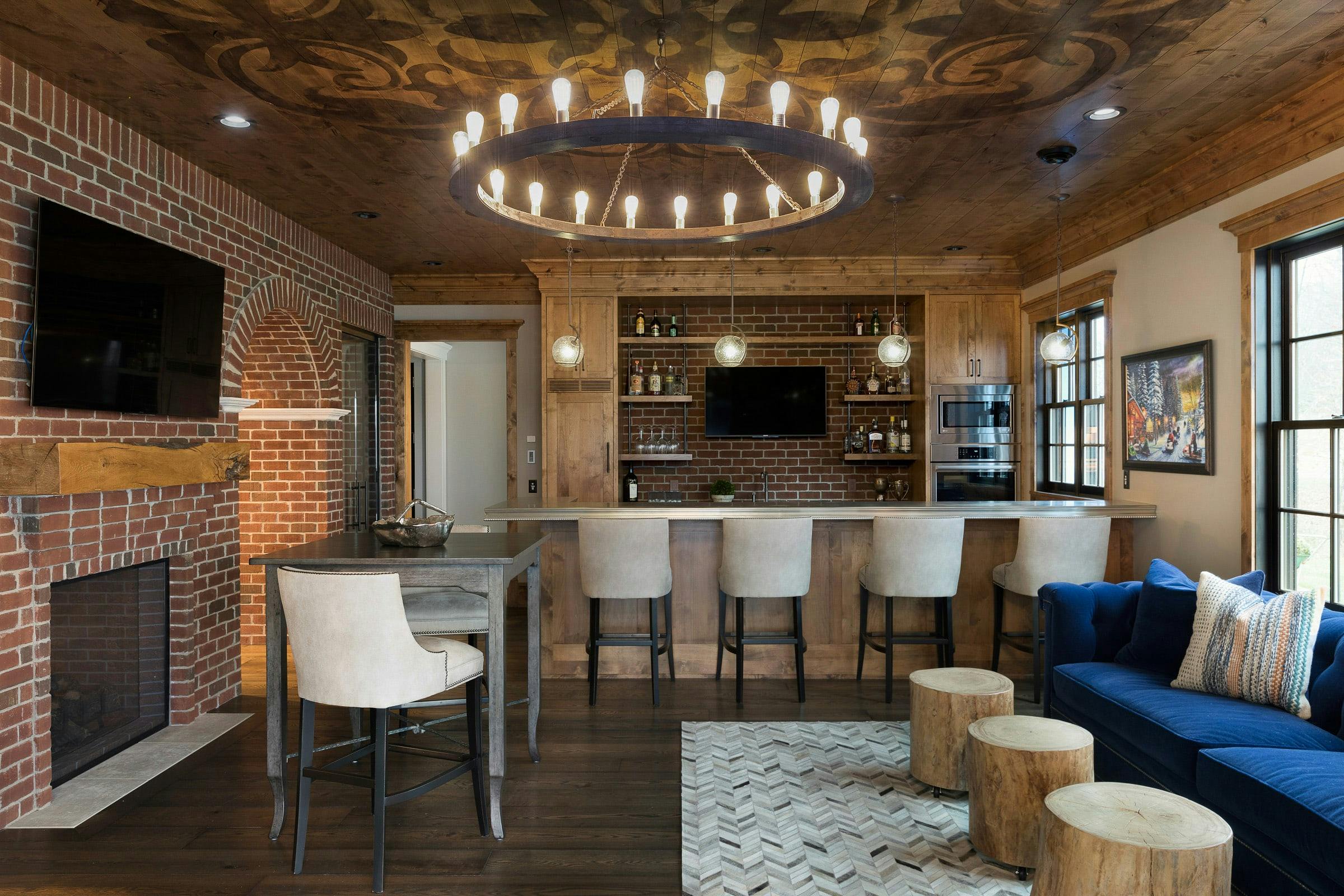 wood and brick bar room with TVs, bar chairs, blue sofa, fireplace