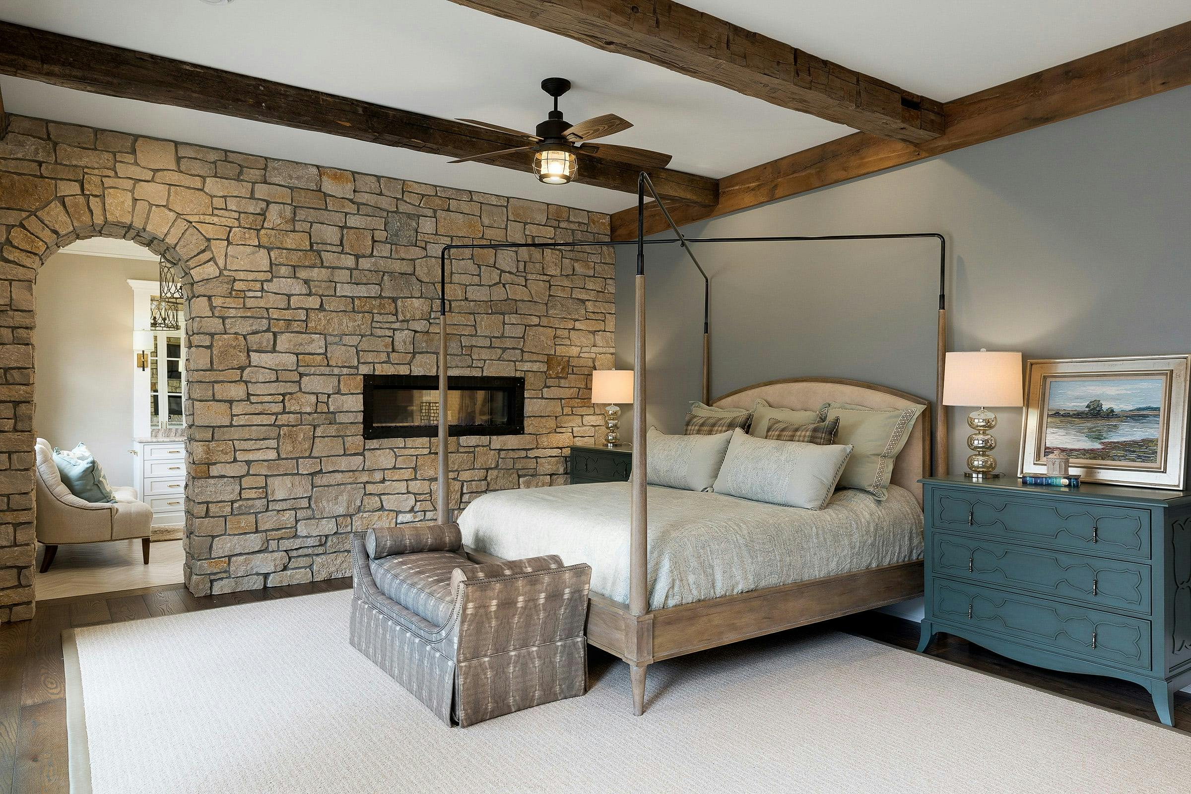 stone wall in bedroom, bed and blue dresser