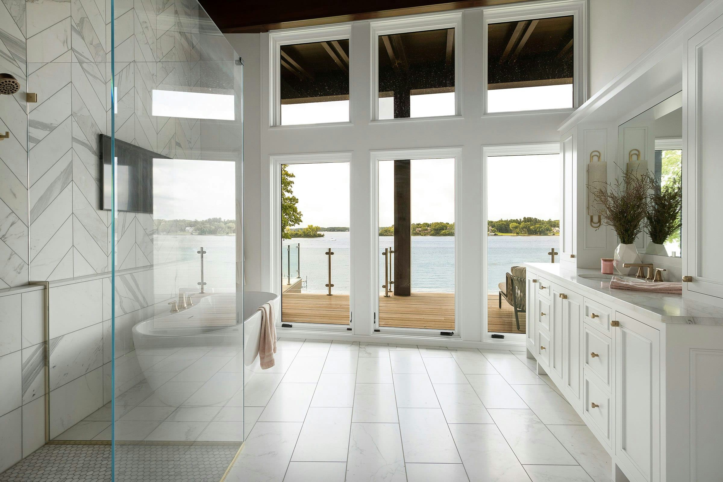 white bathroom with tall windows overlooking lake