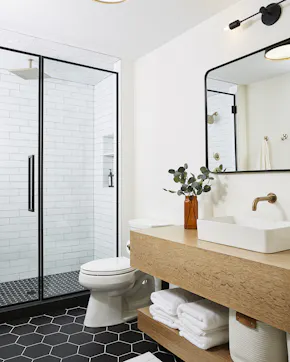 black frame glass shower in black and white bathroom