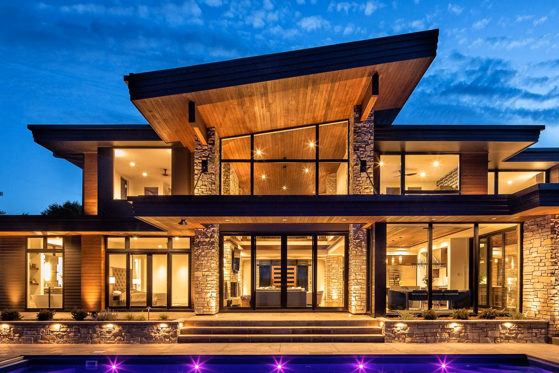 A custom modern mountain exterior with a flat metal roof with exterior stone columns dramatic beauty.