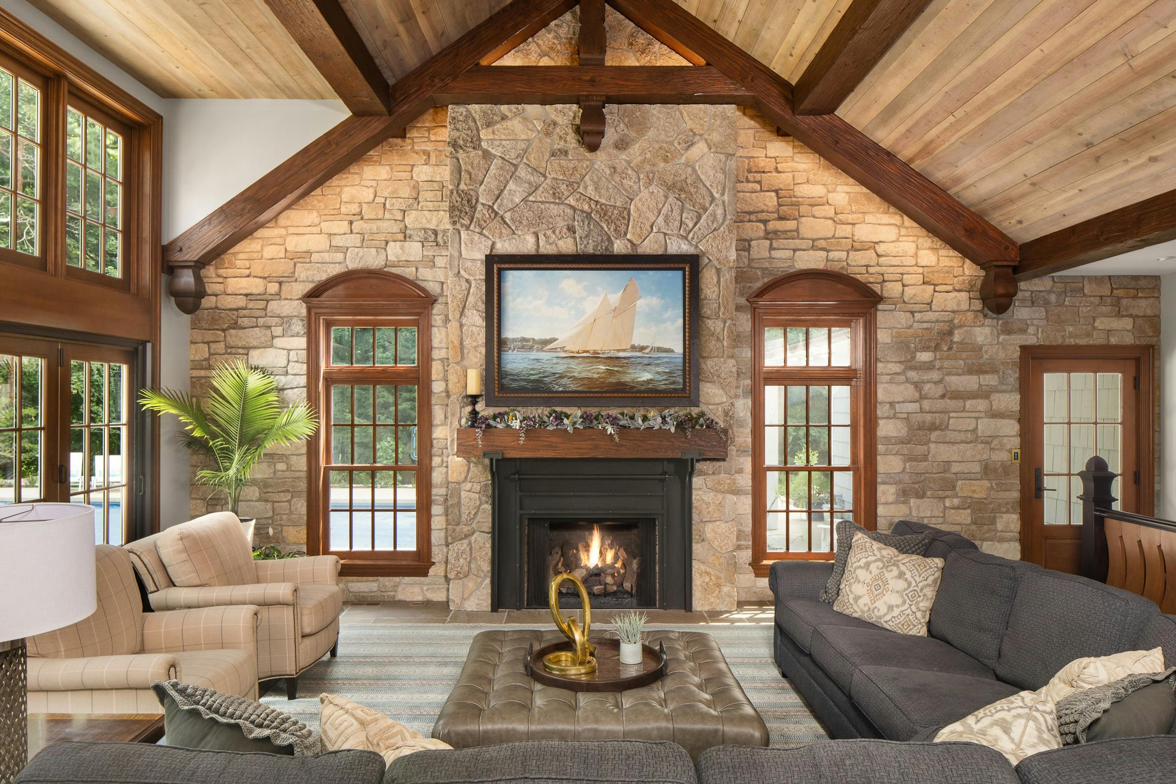 new addition with living room furniture, tall ceiling with beams, stone work, fireplace