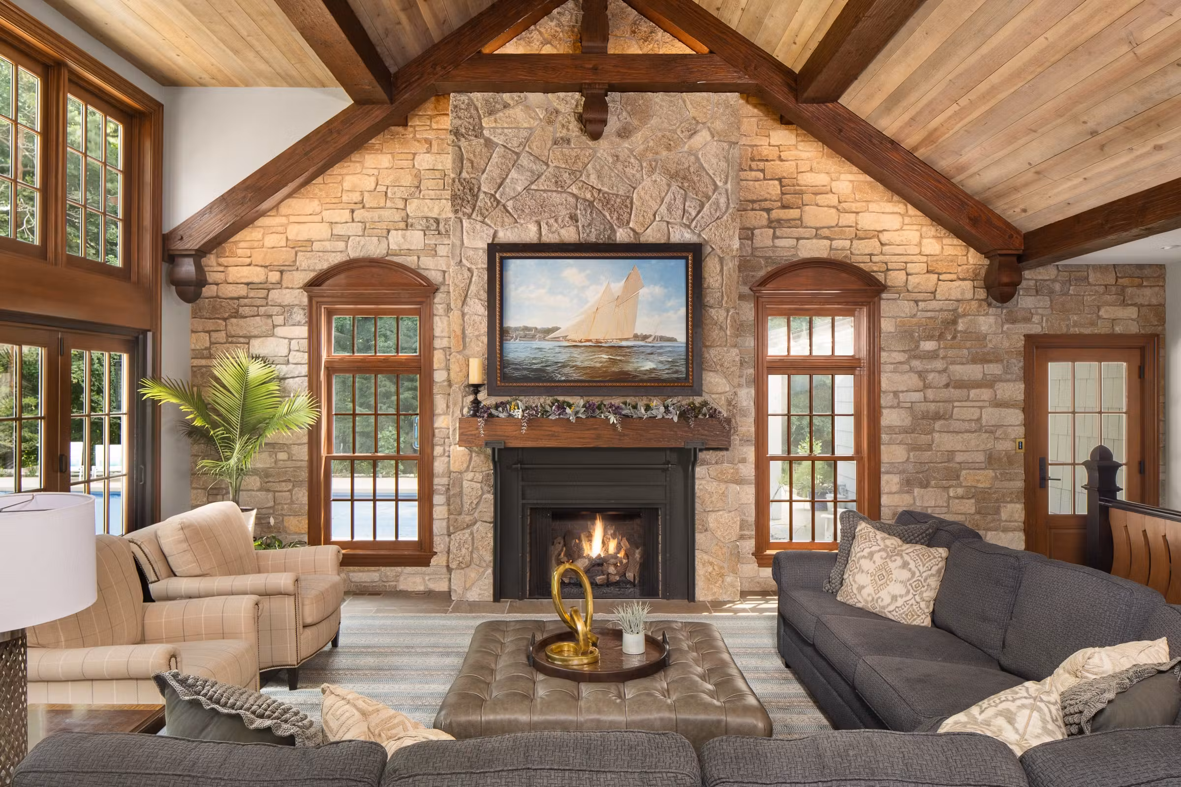 new addition with living room furniture, tall ceiling with beams, stone work, fireplace