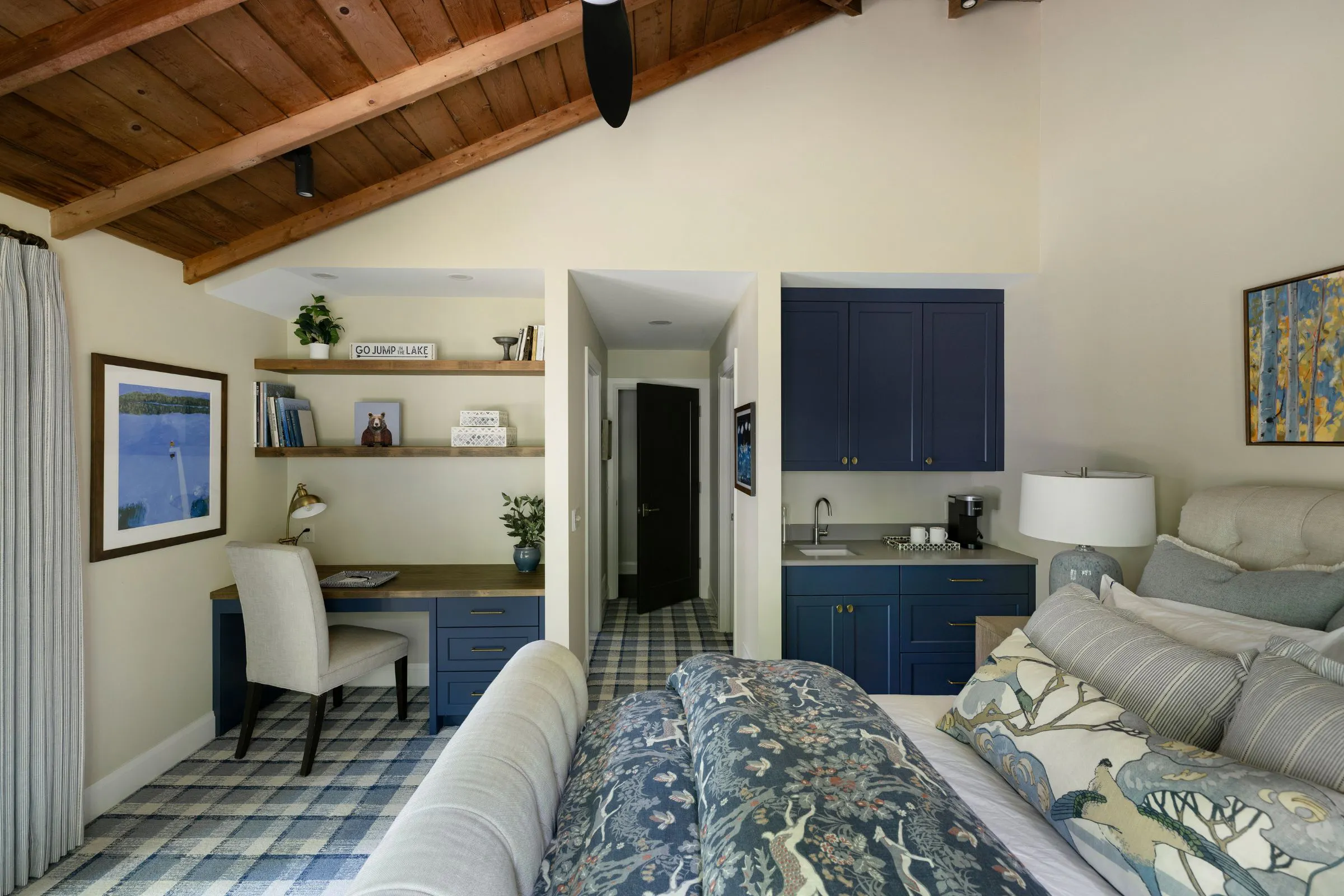 Blue guest bedroom with plaid carpet, patterned bedding and built-in desk