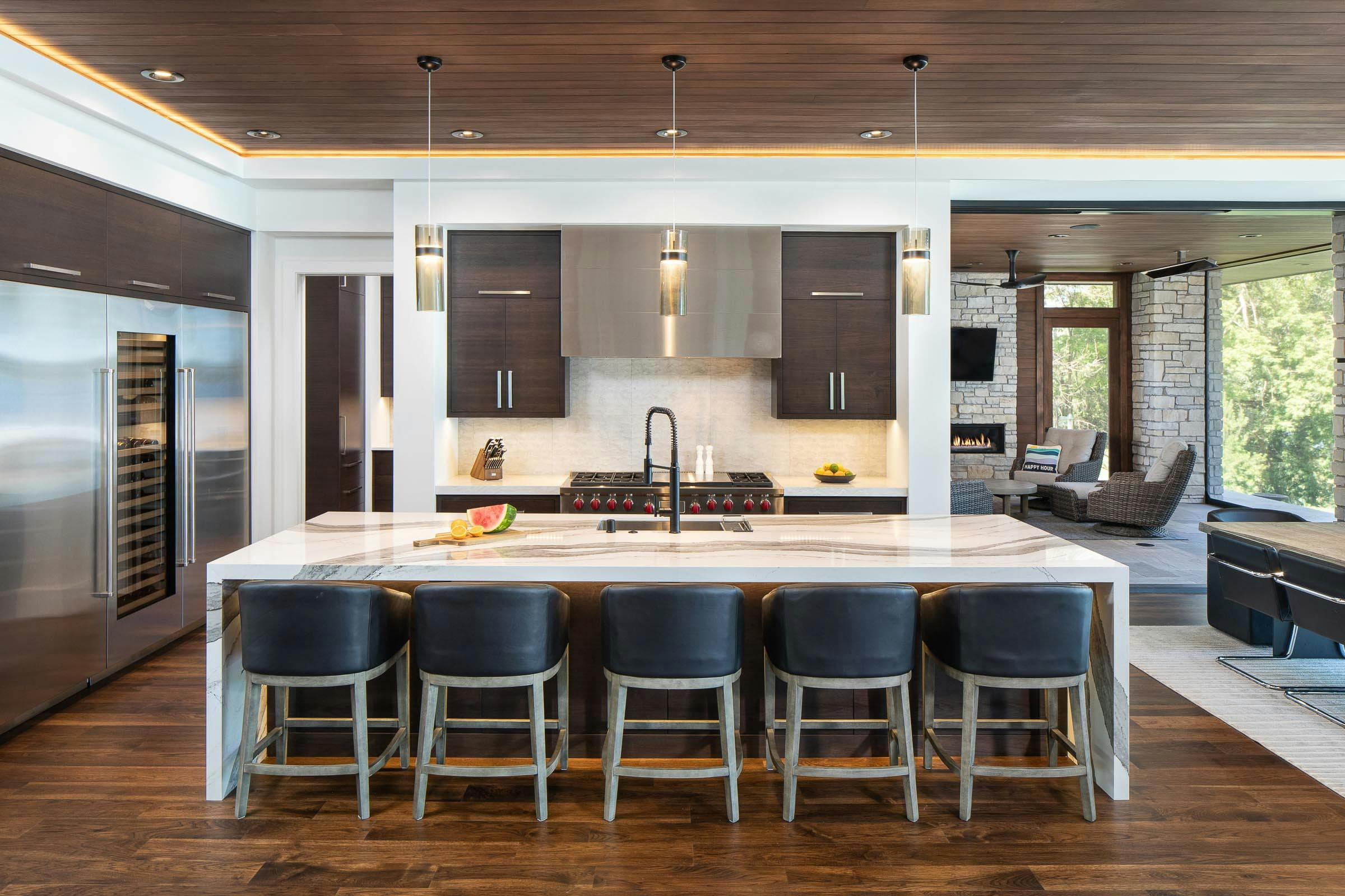 kitchen with waterfall island, refrigerator, stove and hood