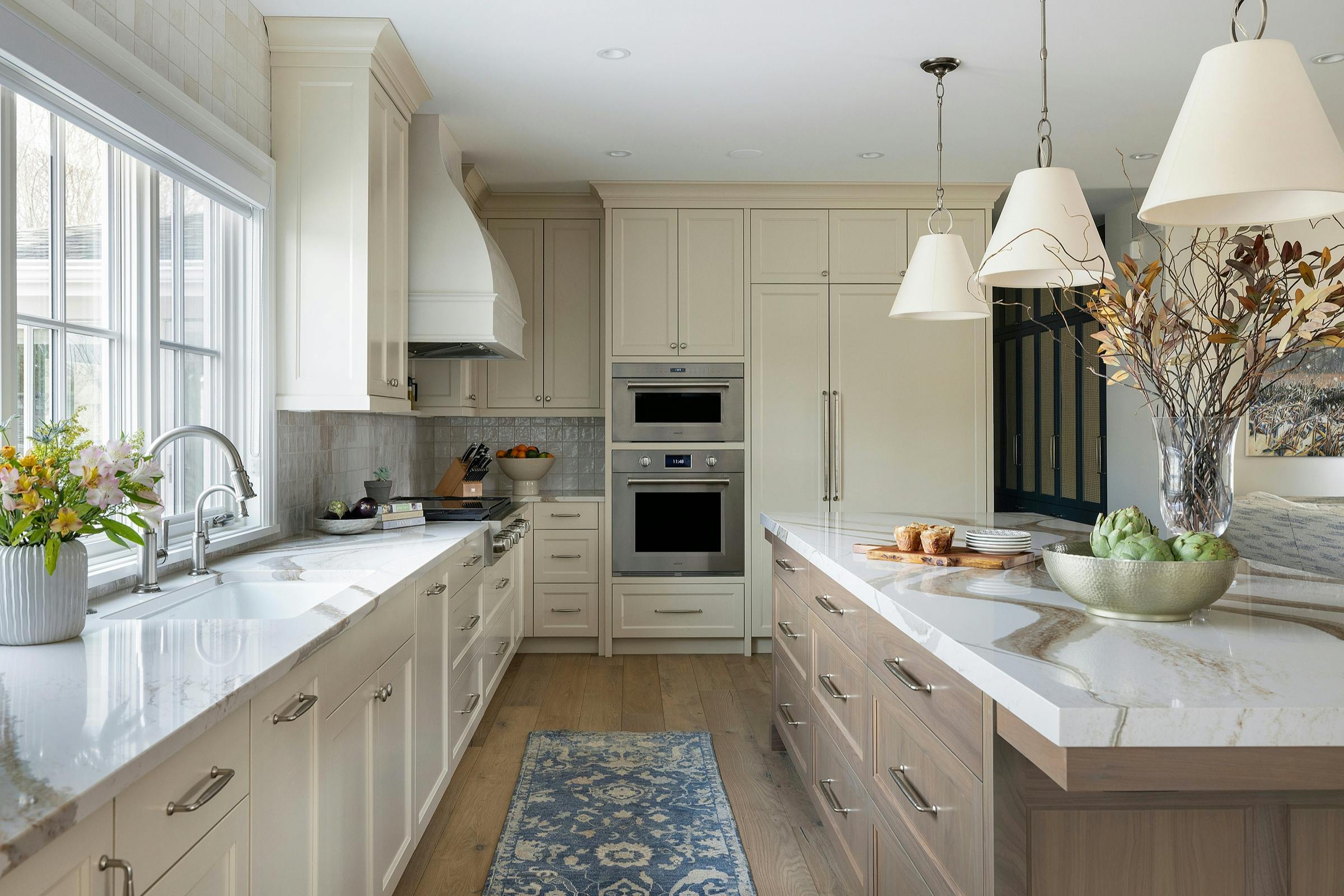 Remodeled kitchen with warm cream cabinetry, double wall oven, and open layout
