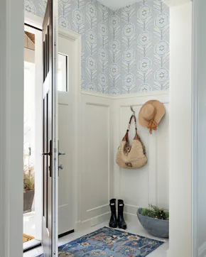 Interior entryway with wallpaper, wainscoting, built-in bench, and hooks for storage