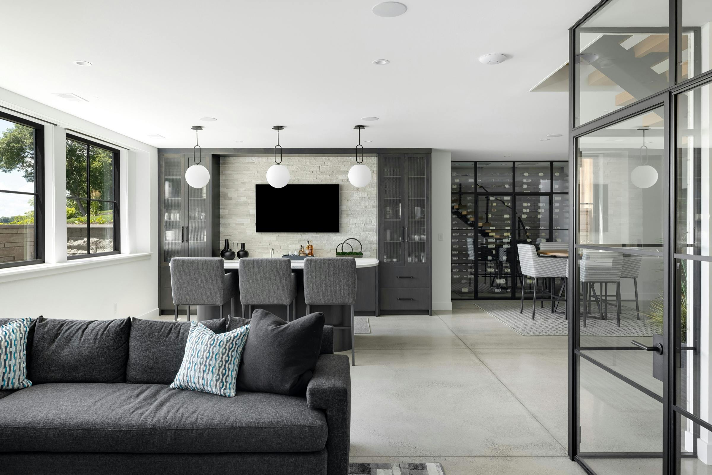 Lower level with polished concrete floors, glass office wall, and lounge area in Lake Minnetonka custom home
