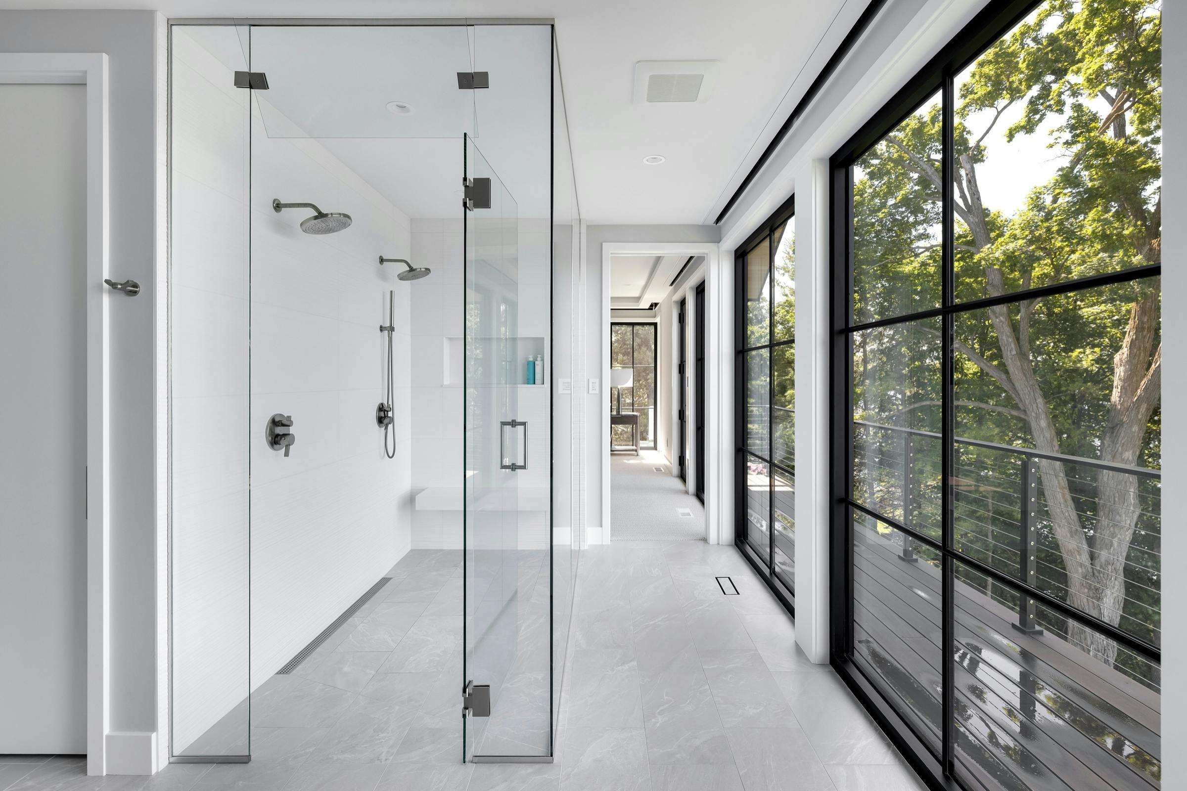 Large walk-in shower with bench, dual showerheads, and textured large-format tile