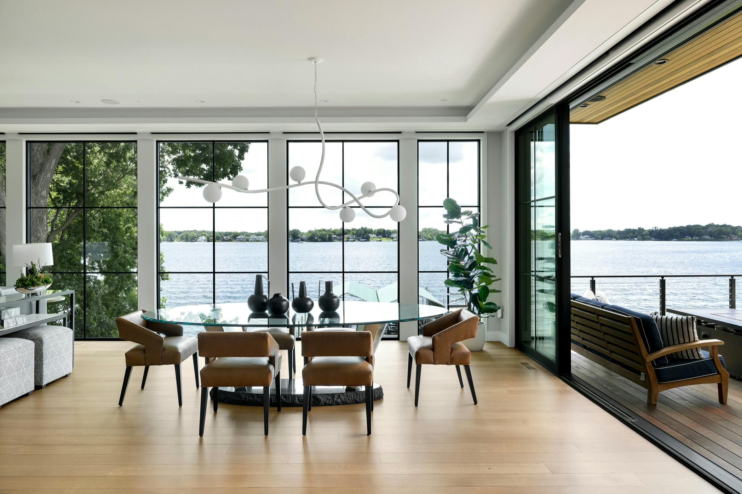 Glass dining table with leather chairs and unobstructed lake views in contemporary Lake Minnetonka home