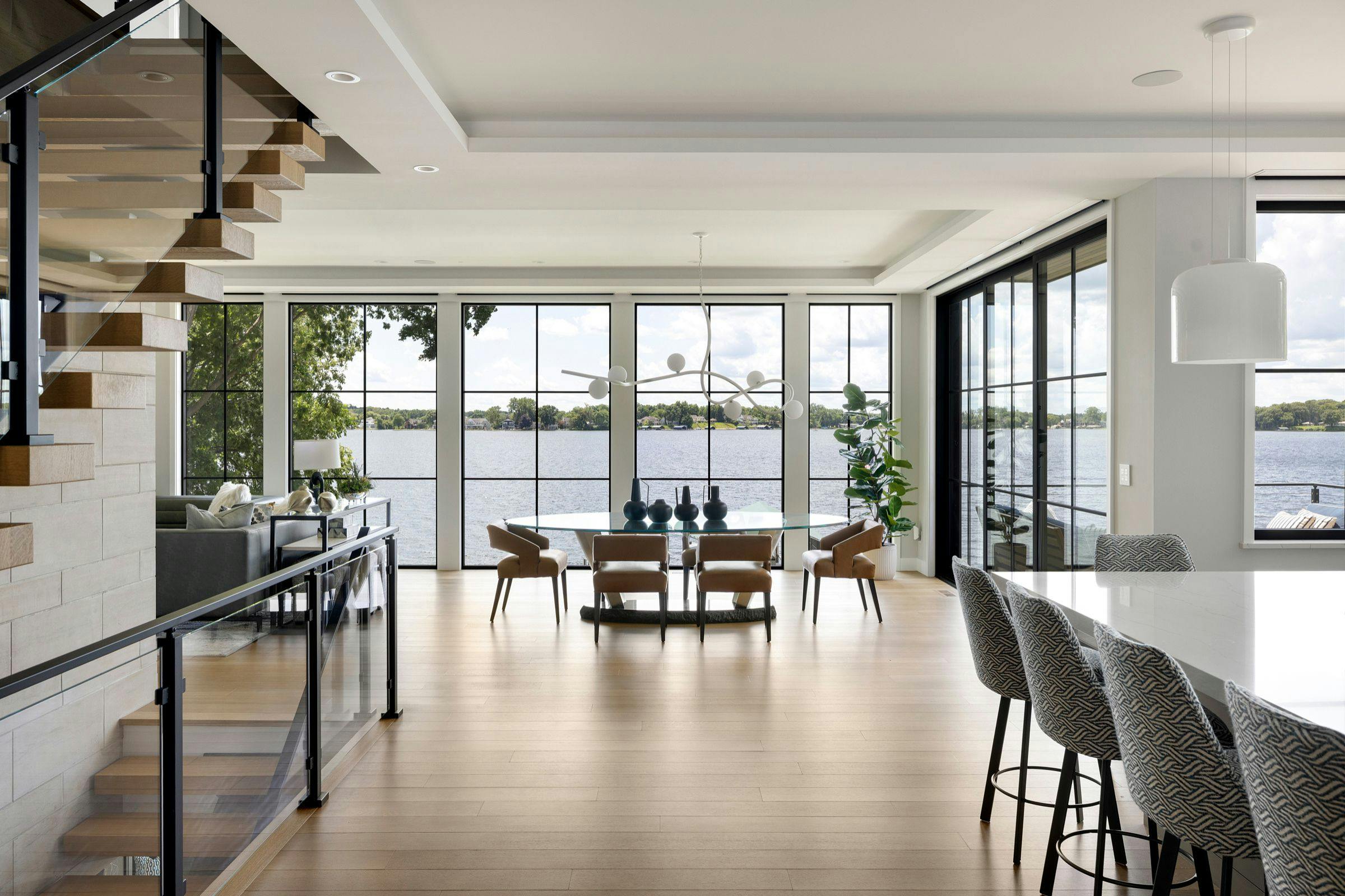 Modern Lake Minnetonka home entry with floating staircase, glass railing, and custom pivot front door
