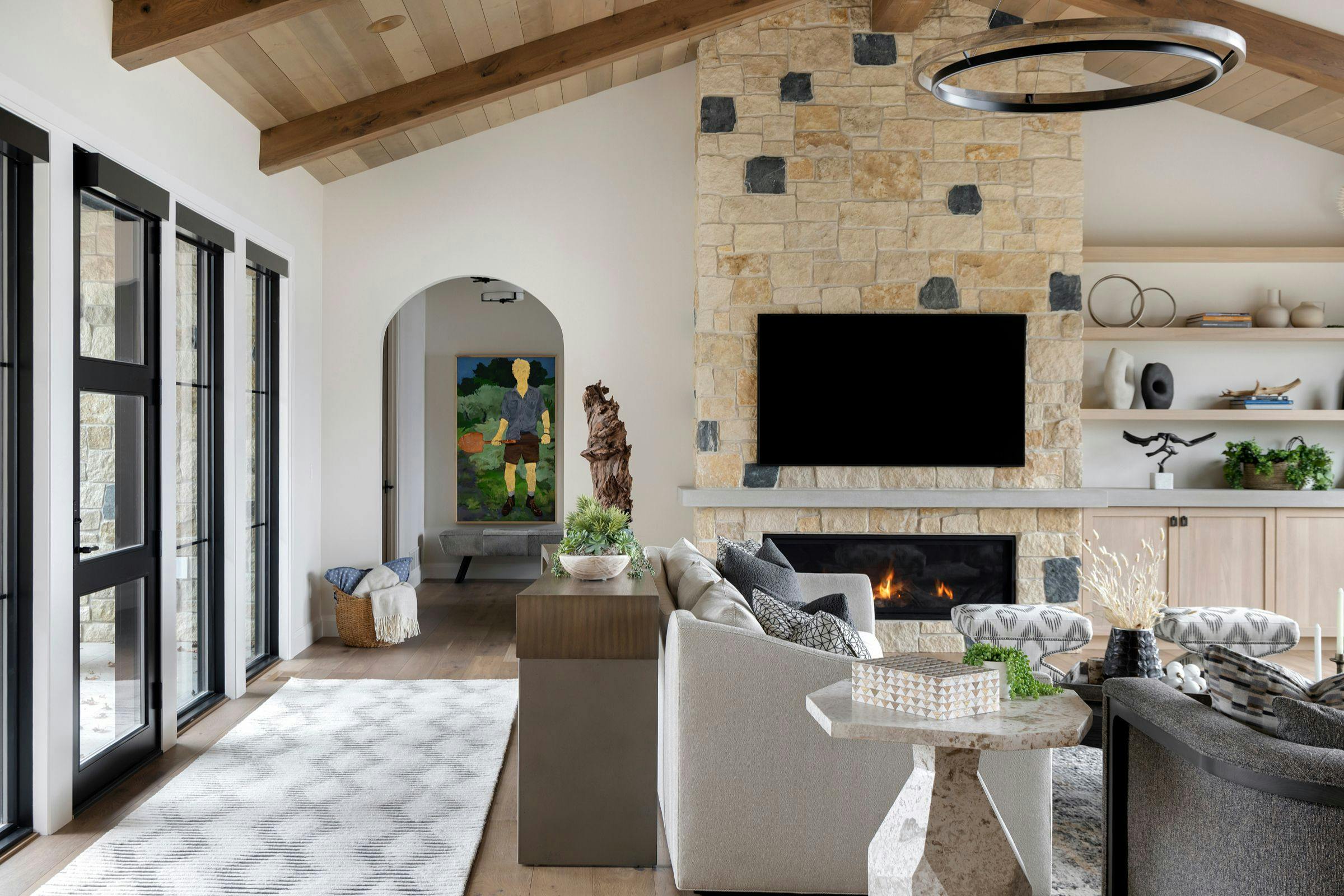 living room with high ceiling with a TV and stacked stone fireplace reaching the ceiling