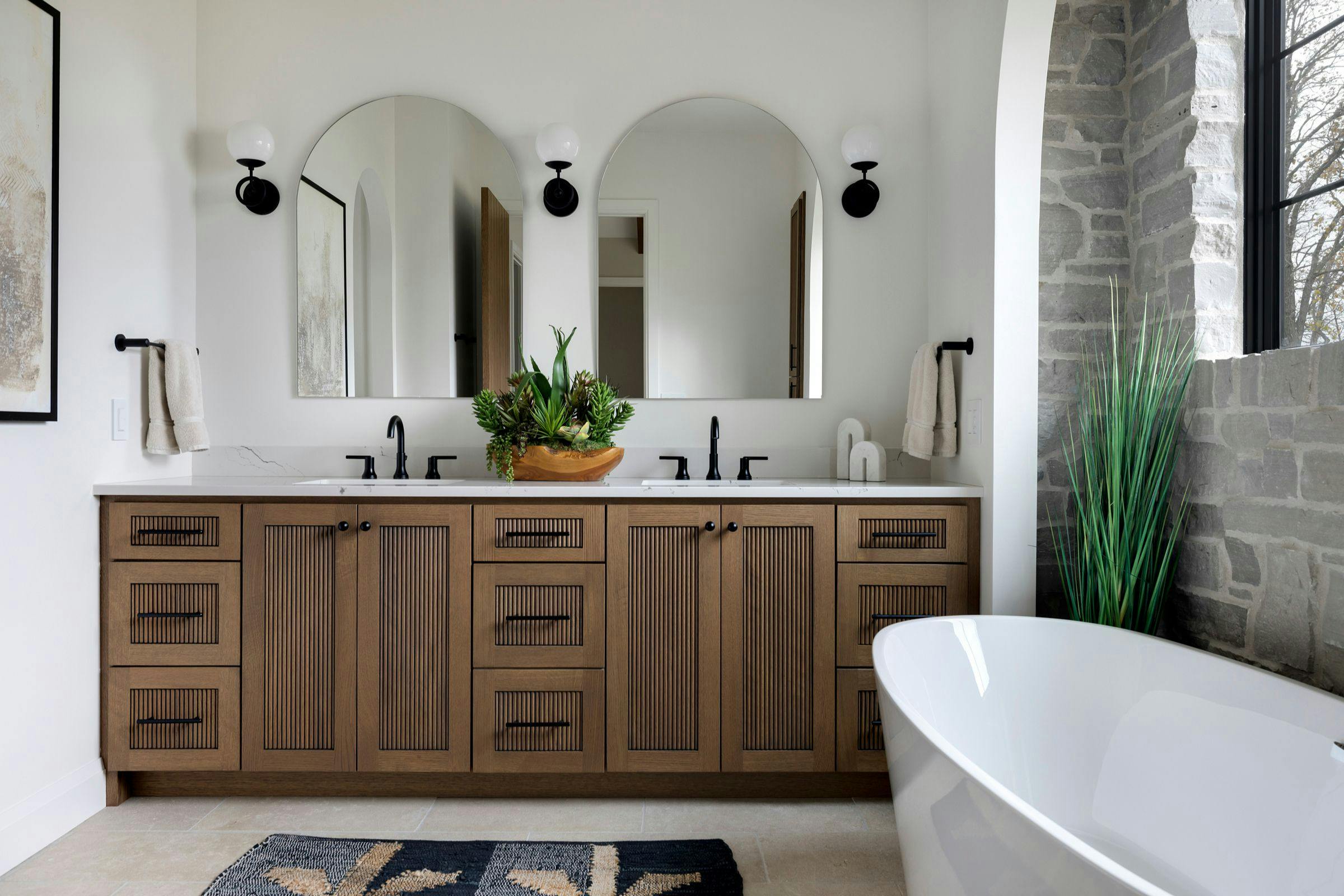 double wood vanity with arch mirrors, freestanding soaking tub